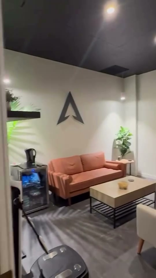 The HEXIS consult room in Great Falls, MT: a salmon sofa, coffee table, and chairs under the HEXIS logo, with plants and warm lighting — the actual room where in-person appointments happen